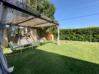 a backyard with a pergola and chairs on the grass at Papas house 2 near Faliraki kalithies in Kalithies