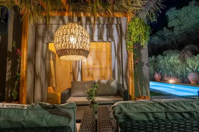 a patio with a couch and a chandelier and a pool at Eros Elysium Retreat Villas in Kalavárda