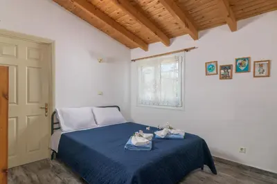 a bedroom with a bed with blue sheets and a window at Billys House in Lardos