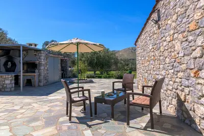 a patio with a table and chairs and an umbrella at Billys House in Lardos