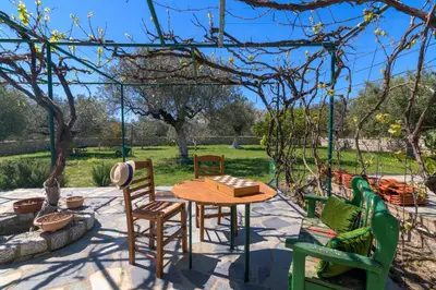 a patio with a table and chairs under a pergola at Billys House in Lardos