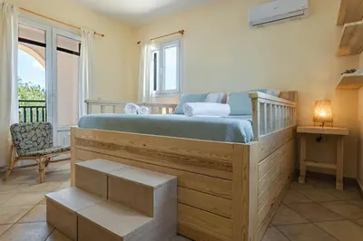 a bedroom with a large wooden bed with blue sheets at Mi Casa South Rhodes in Lachania