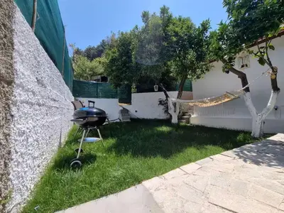 a barbecue grill in the grass next to a wall at The Garden House in Paradisi in Paradeísion