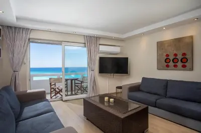 a living room with a blue couch and a television at Molos Seaside Apartment in Rhodes Town