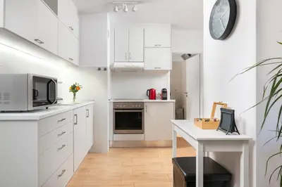 a kitchen with white cabinets and a table and a clock at Elli City Apartment in Rhodes Town