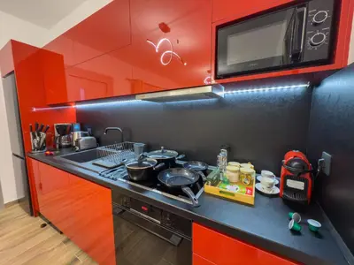 a kitchen with red cabinets and a stove with pots and pans at La casa di pantelis with Luxury Pool in Archangelos