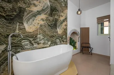 a bath tub in a bathroom with a stone wall at Agkyra Studio in Symi