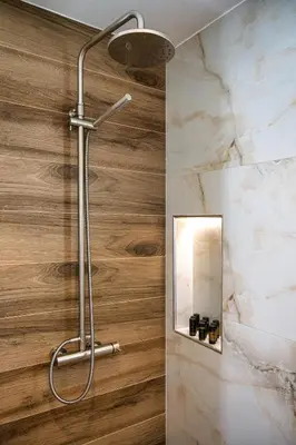 a shower in a bathroom with a wooden wall at The Azure Suites in Haraki
