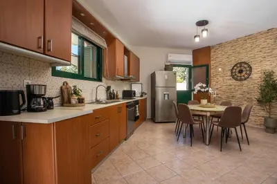 a kitchen with a table and a refrigerator at Lythari Summer Villa in Afantou