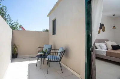 a patio with two chairs and a table and a bed at Lythari Summer Villa in Afantou