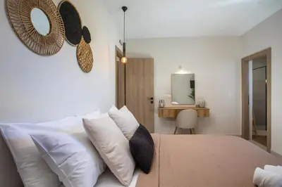a bedroom with a bed with white pillows and a mirror at Lythari Summer Villa in Afantou
