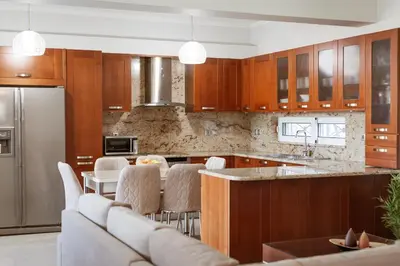 a kitchen with wooden cabinets and a bar with white chairs at Villa Afandou Bliss with private pool & panoramic sea view in Afantou