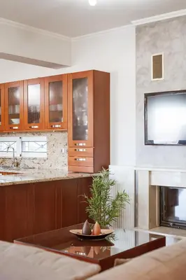 a kitchen with wooden cabinets and a glass table at Villa Afandou Bliss with private pool & panoramic sea view in Afantou
