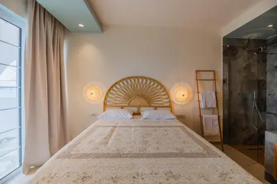 a bedroom with a large bed and a shower at Delfini Pearl Stegna Beach in Archangelos