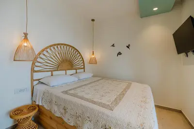 a bedroom with a bed and a tv and birds on the wall at Delfini Pearl Stegna Beach in Archangelos