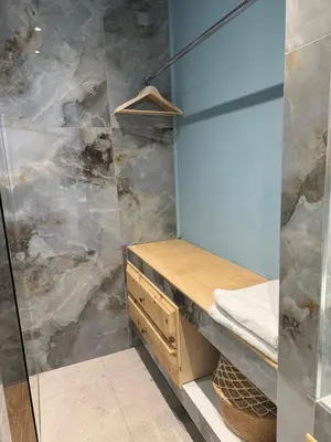 a bathroom with a shower with a wooden vanity and a glass wall at Delfini Pearl Stegna Beach in Archangelos