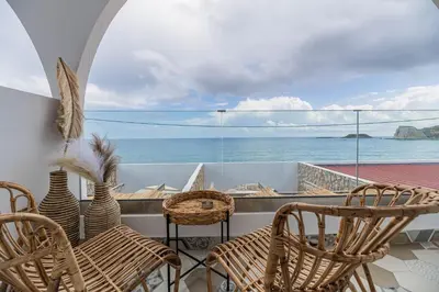 a balcony with chairs and a view of the ocean at Delfini Pearl Stegna Beach in Archangelos