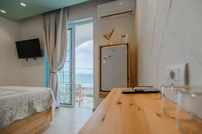 a bedroom with a bed and a table with a mirror at Delfini Pearl Stegna Beach in Archangelos