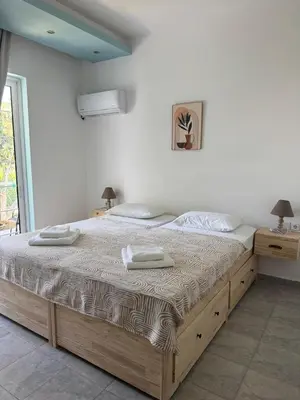 a bedroom with a large bed with two towels on it at Delfini Pearl Stegna Beach in Archangelos
