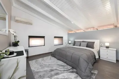 a white bedroom with a large bed and a rug at Golden sand 4 in Ialyssos