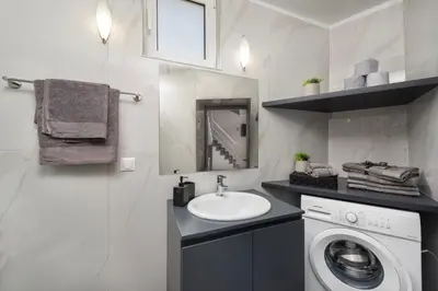 a bathroom with a washing machine and a sink at Golden sand 4 in Ialyssos