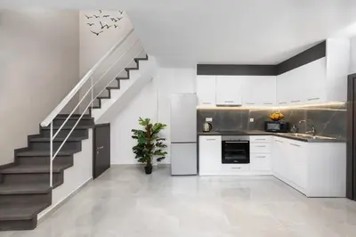 a kitchen with white cabinets and a staircase at Golden sand 4 in Ialyssos