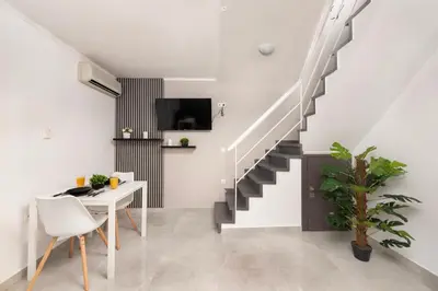 a living room with a table and a staircase at Golden sand 4 in Ialyssos