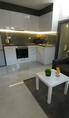 a living room with a white table and a kitchen at Golden sand 4 in Ialyssos
