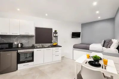 a kitchen with white cabinets and a living room at Golden sand 5 in Ialyssos