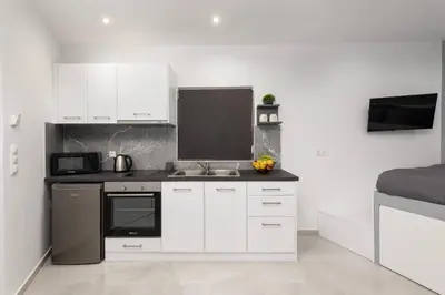a white kitchen with a sink and a microwave at Golden sand 5 in Ialyssos