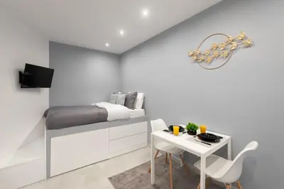 a white bedroom with a bed and a table at Golden sand 5 in Ialyssos