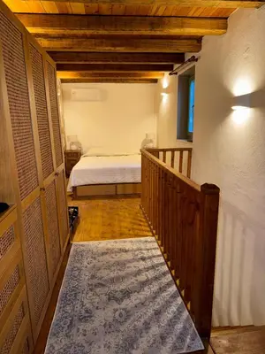a bedroom with a bed and a hallway with a staircase at Aetheria Traditional House 2 in Koskinou
