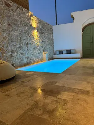a swimming pool in a room with a stone wall at Aetheria Traditional House 2 in Koskinou