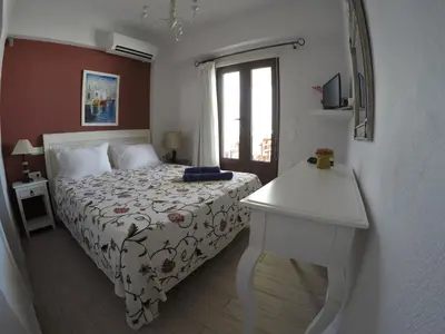 a bedroom with a bed and a table and a window at Eleni Boutique Apartment in Líndos