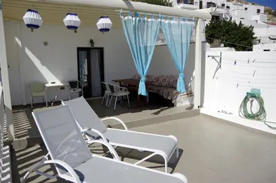 a patio with chairs and a bed and a table at Eleni Boutique Apartment in Líndos