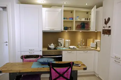 a kitchen with white cabinets and a wooden table at Eleni Boutique Apartment in Líndos