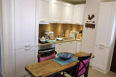 a kitchen with white cabinets and a wooden table at Eleni Boutique Apartment in Líndos