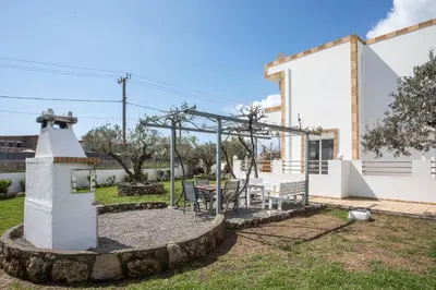 a garden with a table and a monument in front of a house at Ennisfree Villa in Kiotari