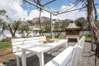 a white picnic table with two white chairs and a fireplace at Ennisfree Villa in Kiotari