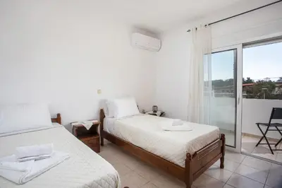 a bedroom with two beds and a balcony at Ennisfree Villa in Kiotari