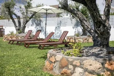 a row of chairs and an umbrella in a yard at Ennisfree Villa in Kiotari