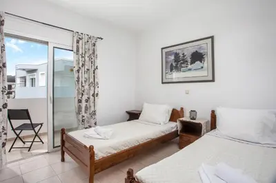 a bedroom with two beds and a balcony at Ennisfree Villa in Kiotari