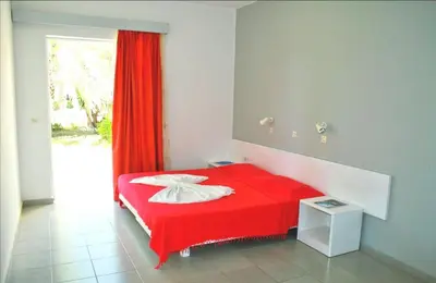 a red bed in a room with a window at Paras Beach Apartments in Ialyssos