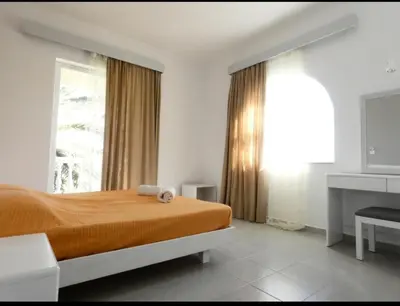 a bedroom with a bed and a large window at Paras Beach Apartments in Ialyssos