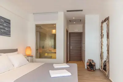 a bedroom with a white bed and a mirror at Lindia Athena Luxury Villas in Líndos