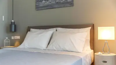 a bedroom with a bed with white pillows and a lamp at Lindia Athena Luxury Villas in Líndos