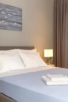a bedroom with a bed with white sheets and a lamp at Lindia Athena Luxury Villas in Líndos