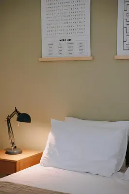 a bed with a white pillow and a lamp on a table at Leoni's House near the Beach in Kremasti