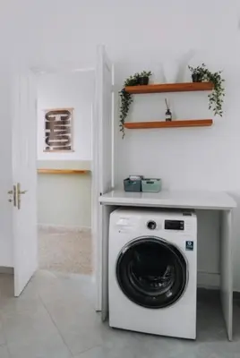 a white laundry room with a washing machine under a counter at Leoni's House near the Beach in Kremasti