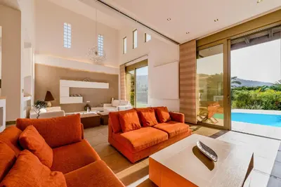 a living room with orange furniture and a pool at Filerimos Oasis Villa in Ialyssos